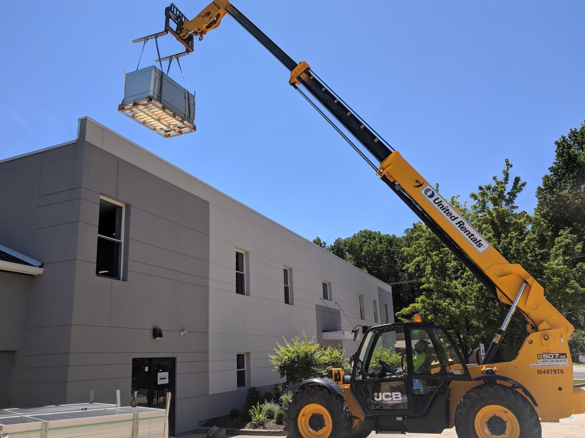 Solar energy project in progress with crane lifting materials onto a building rooftop